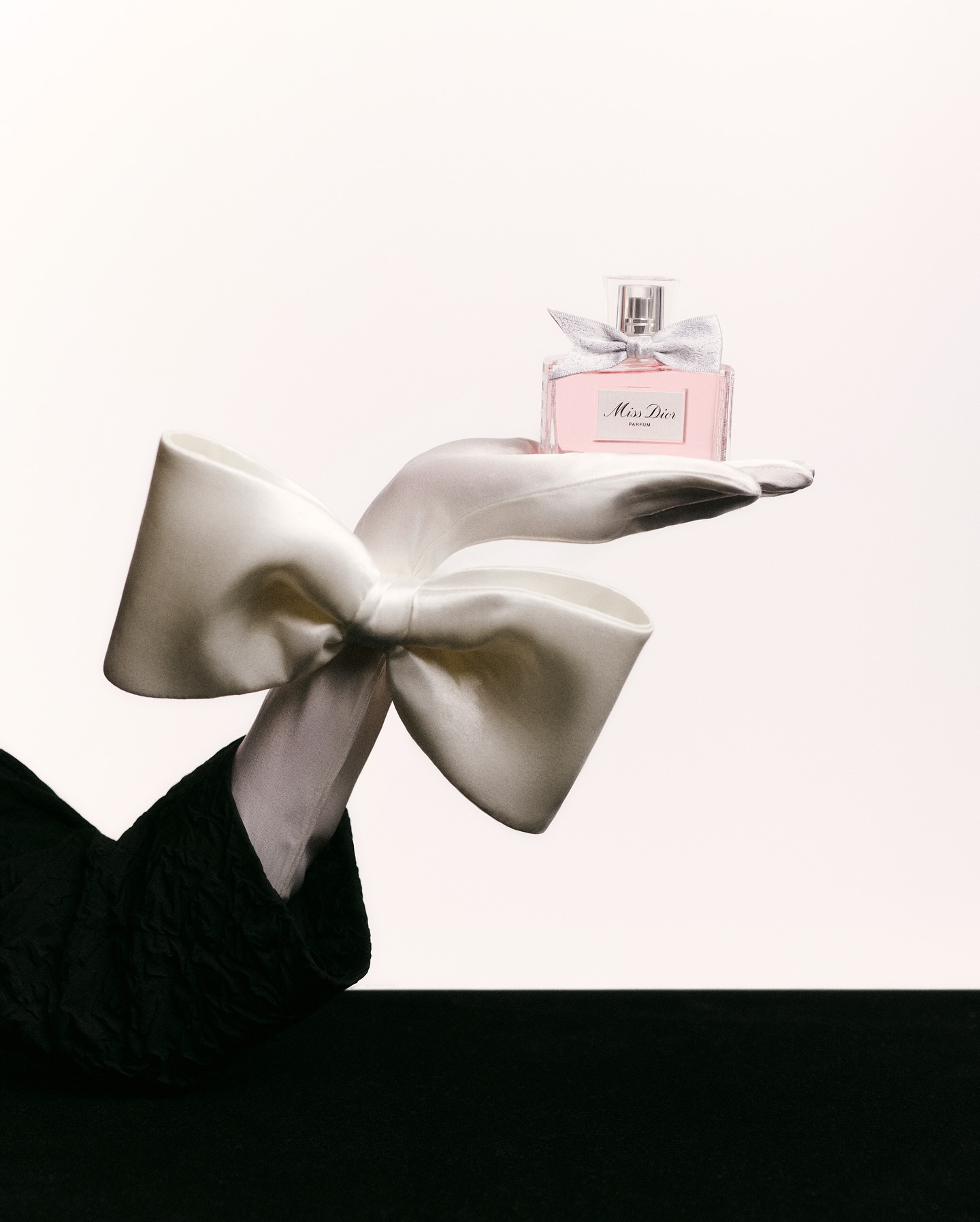 Frasco de Miss Dior sobre luva com laço